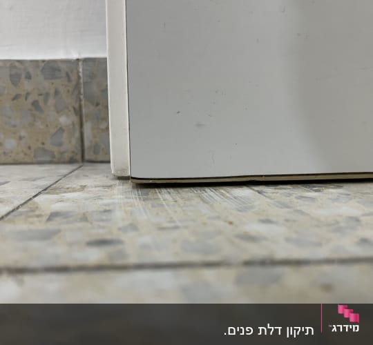 תחתית דלת לבנה על רצפת אריחים